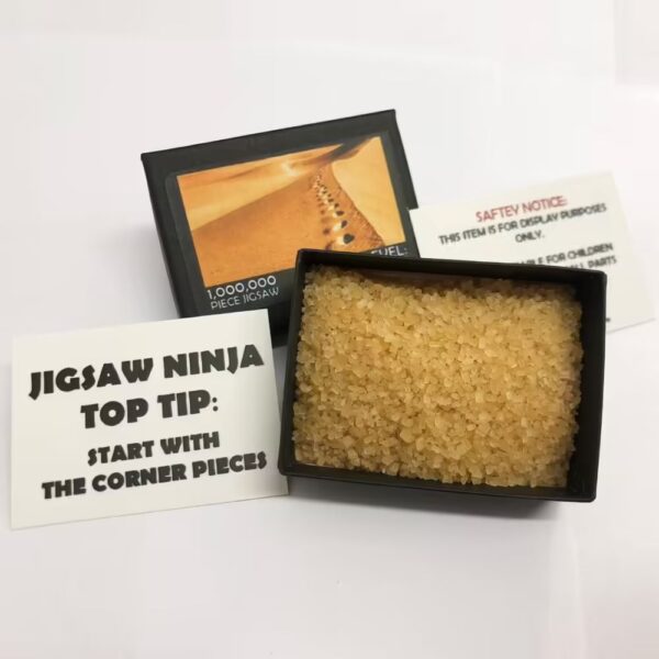 One Million Piece Jigsaw Puzzle box, accompanied by a Jigsaw Ninja tip card that reads 'Start with the corner pieces' and a safety notice card. A fun prank gift for puzzle lovers.