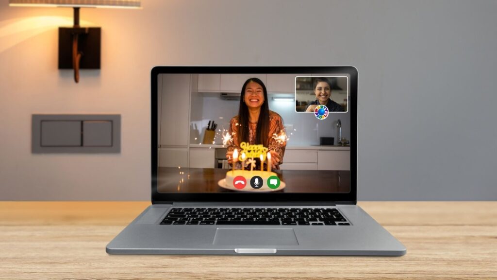 Virtual birthday party hosted online, with a person blowing out candles on a cake via a laptop video call.